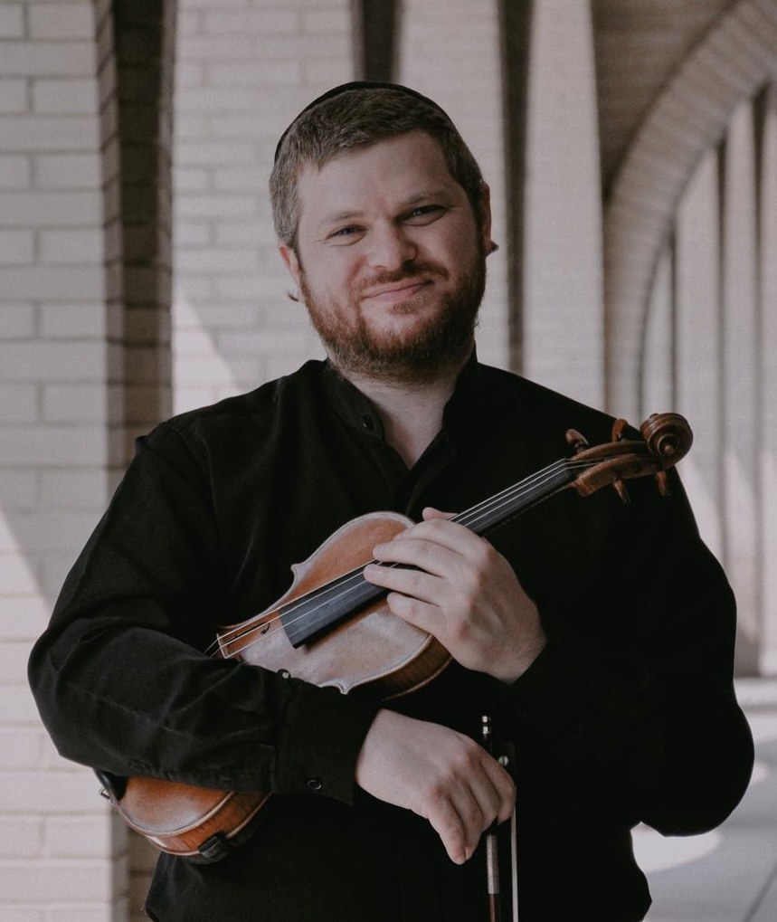 Dr. Yonatan Grinberg smiling and holding his violin